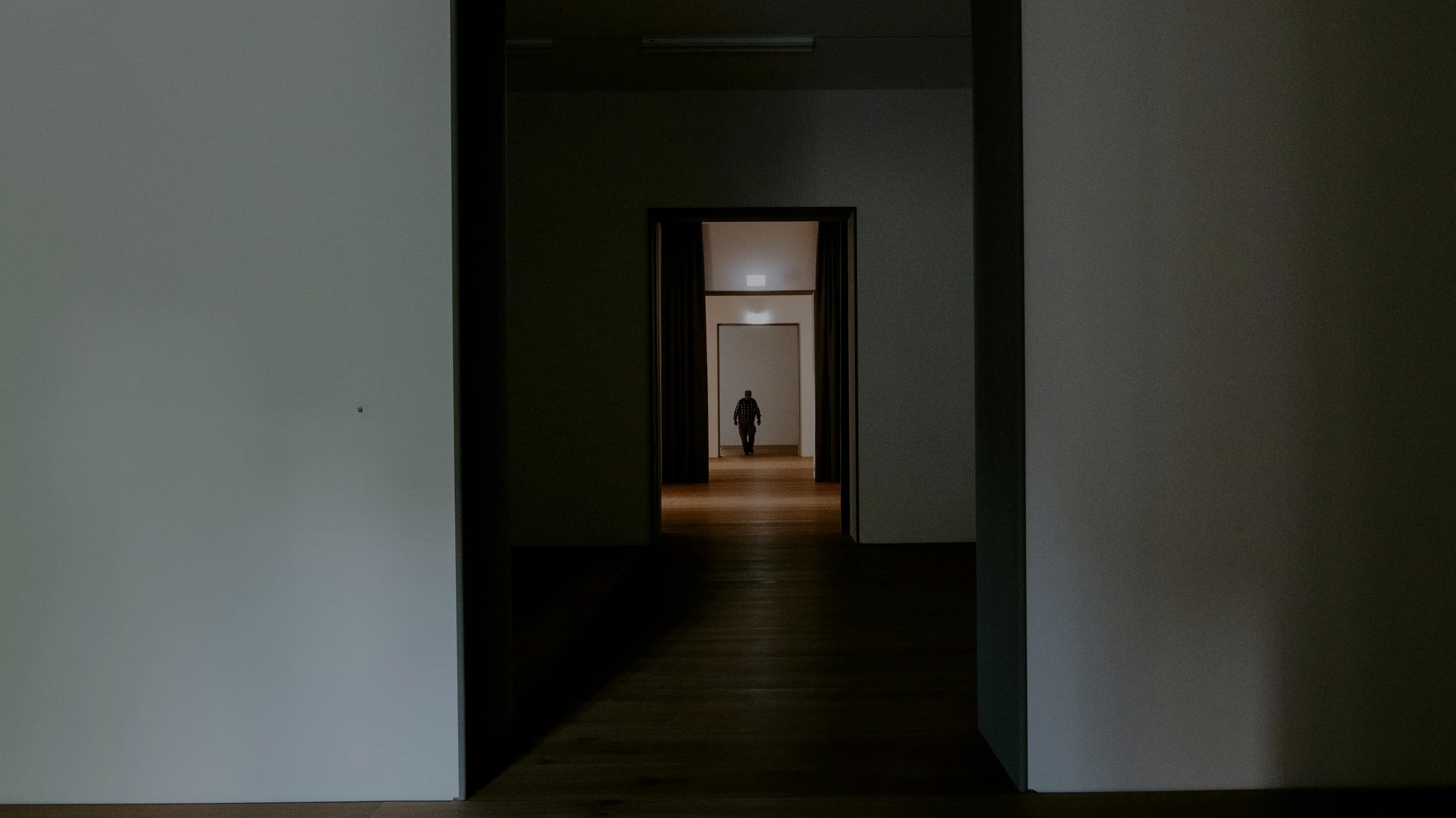 A dark corridor leading to a lit threshold