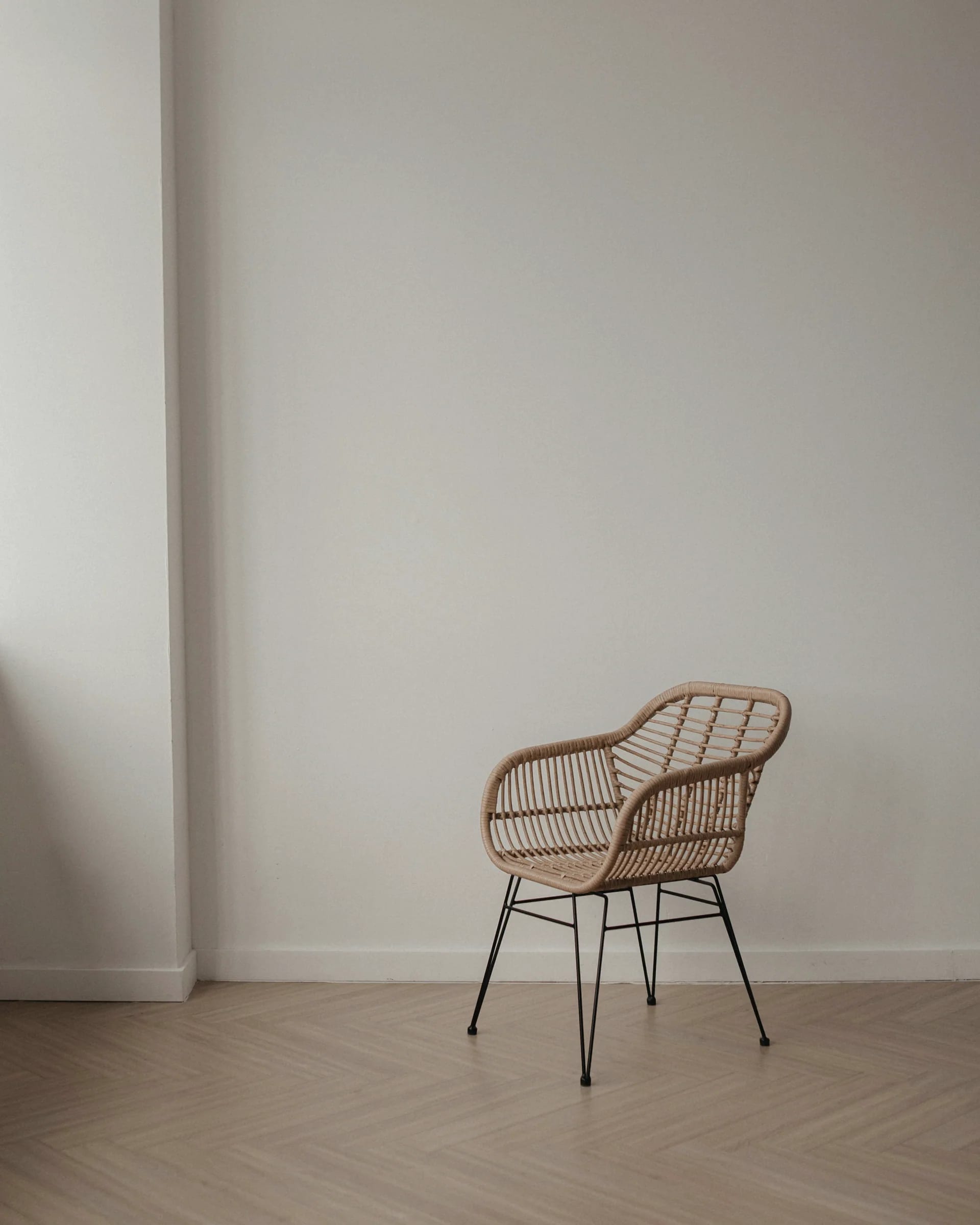 A woven chair against a bare plaster wall