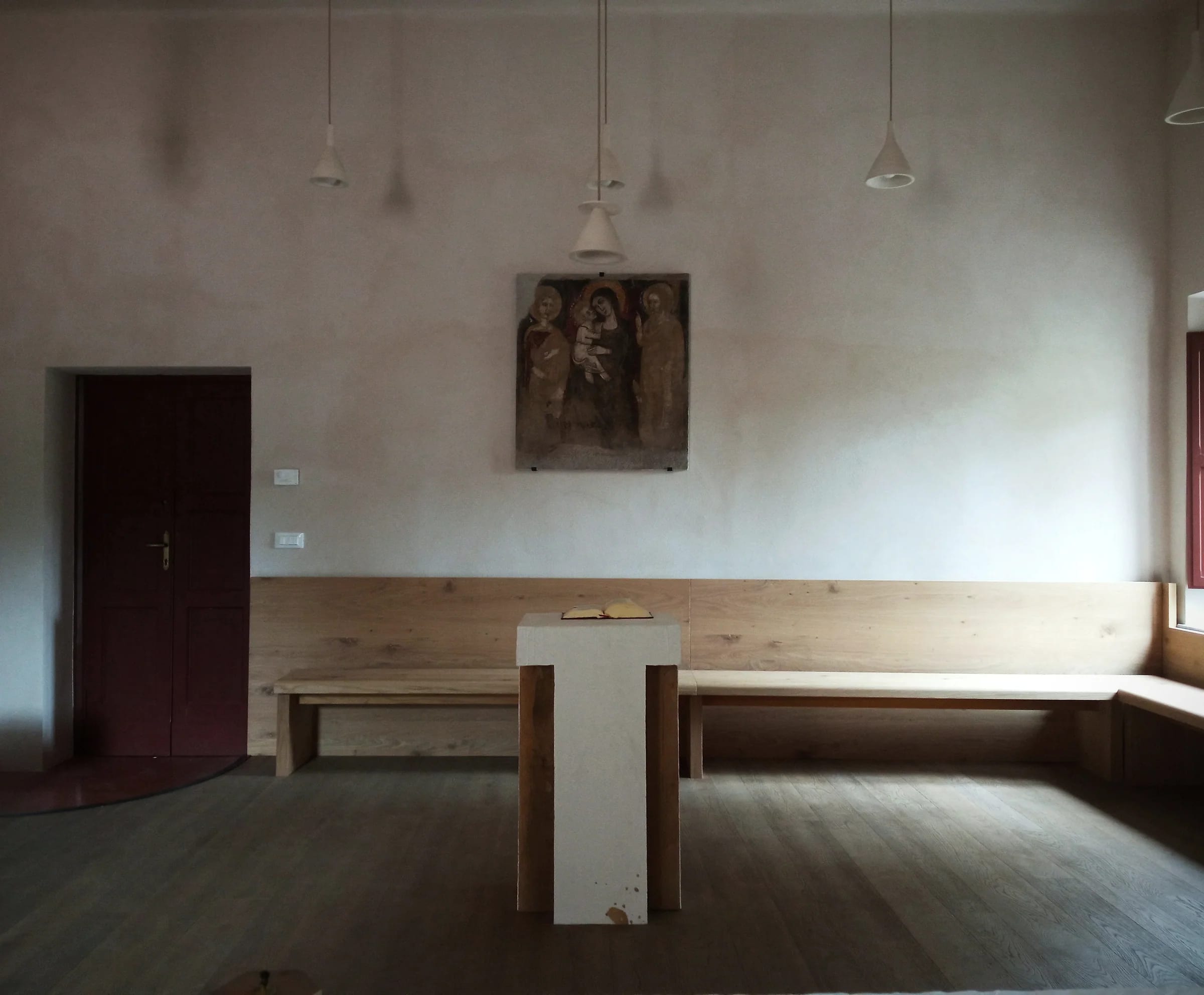 A long oak dining room with pendant lights and a plaster wall