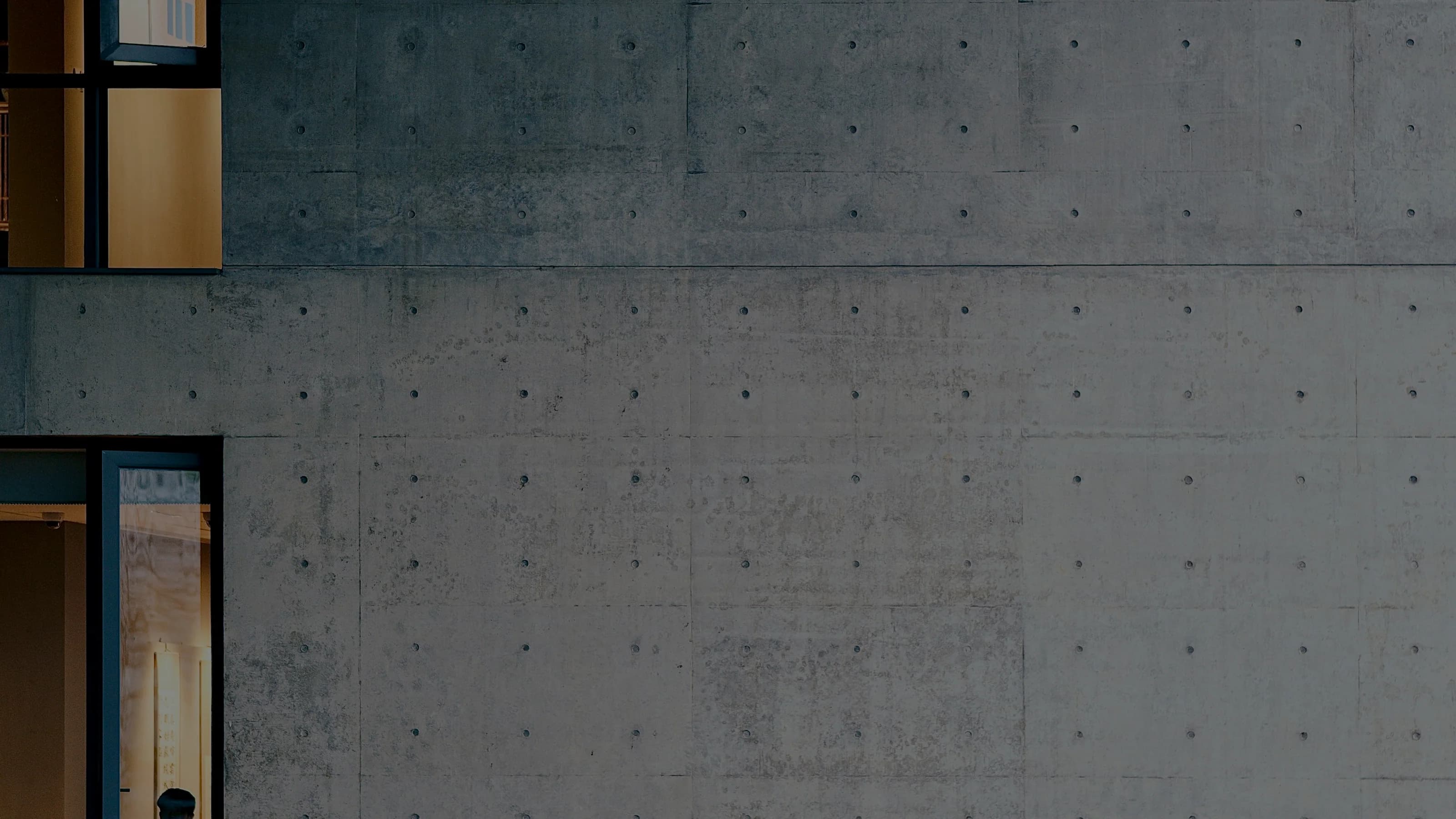 A board-formed concrete wall with a single deep window opening