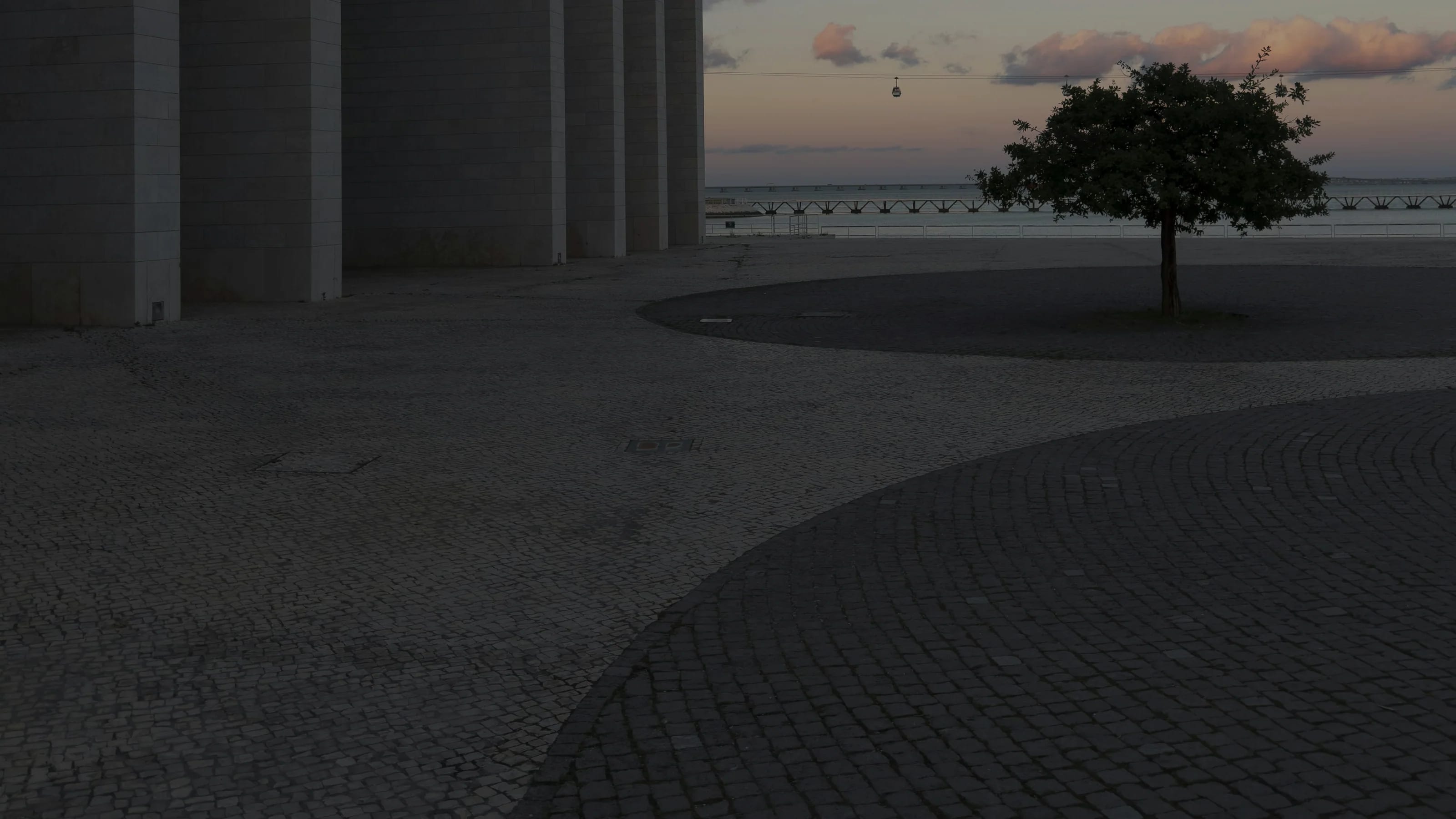 A concrete colonnade facing open water at dusk